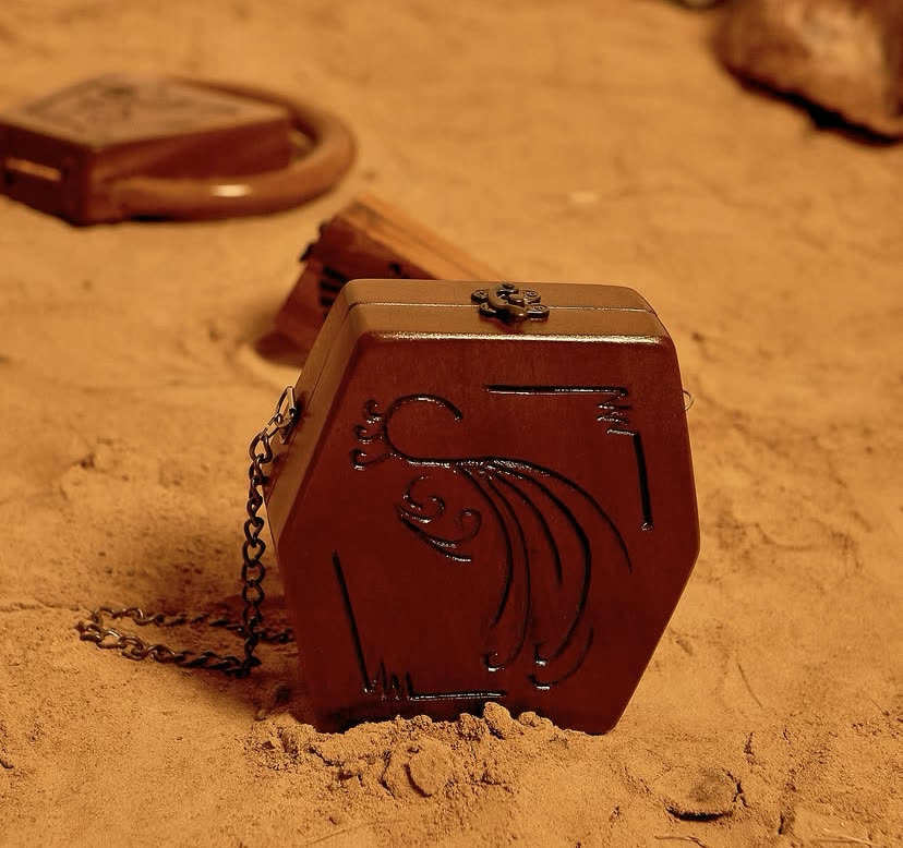 The Crossbody ankyem wooden bag, a hand-carved walnut case with a chain strap in a Cherry finish, by Phyll Quahsey.